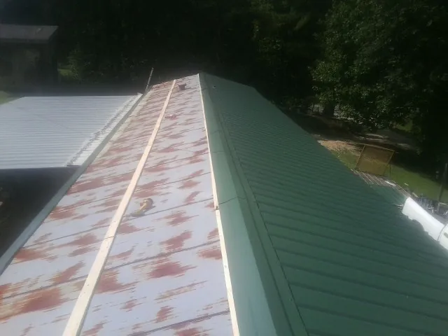 Old rusted panels beside newly installed green metal roofing — Wind Damage Roof Repair by Roofing Brothers in Lakemore