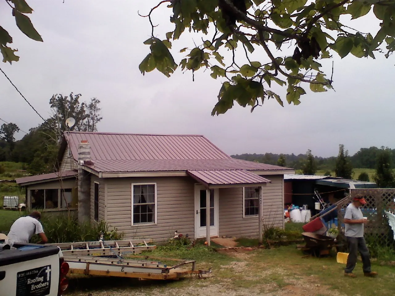 Crew finishing a mauve metal roof on a small farmhouse in Lakemore