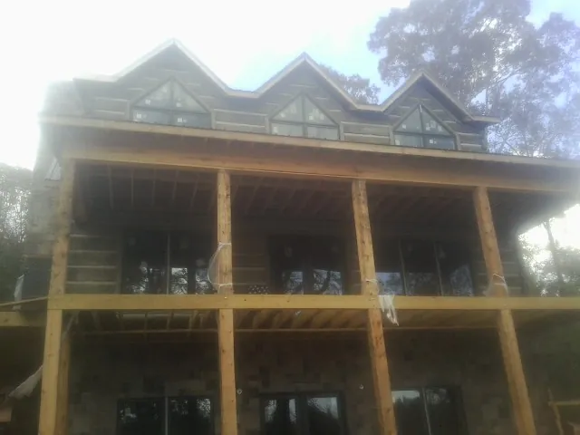 Dormers and porch framing on a large log home under construction — Roof Coating work by our crew in Lakemore
