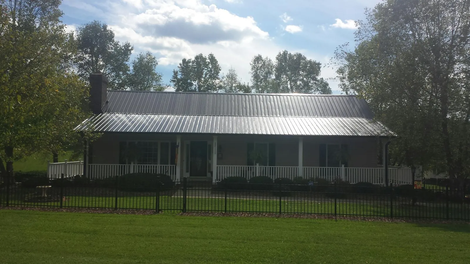 Gray metal roof on a brick ranch with a full width front porch — Gutter Guard Installation work by our crew in Lakemore