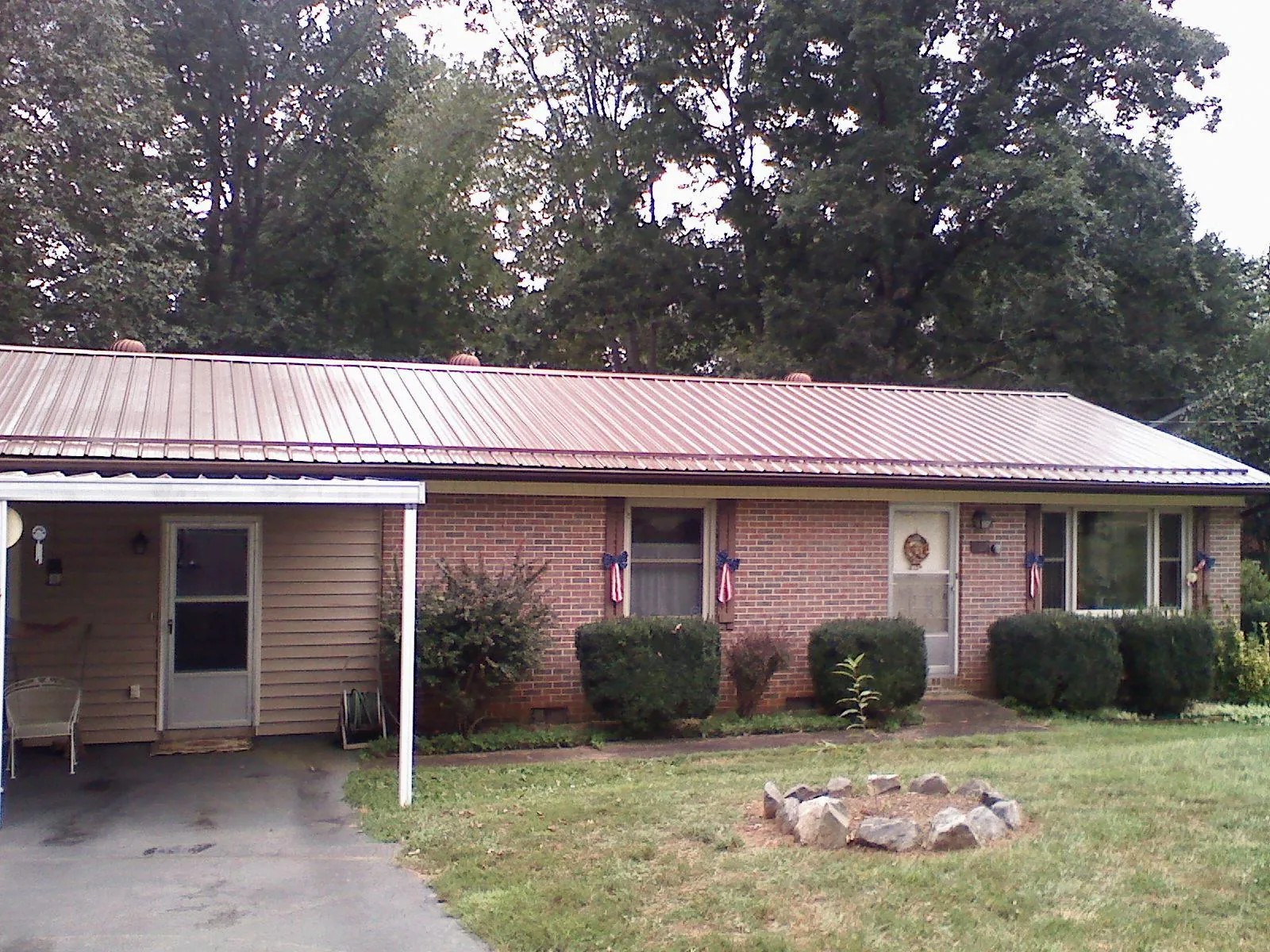 Bronze metal roof and carport on a brick ranch home — Roof Repair work by our crew in Lakemore