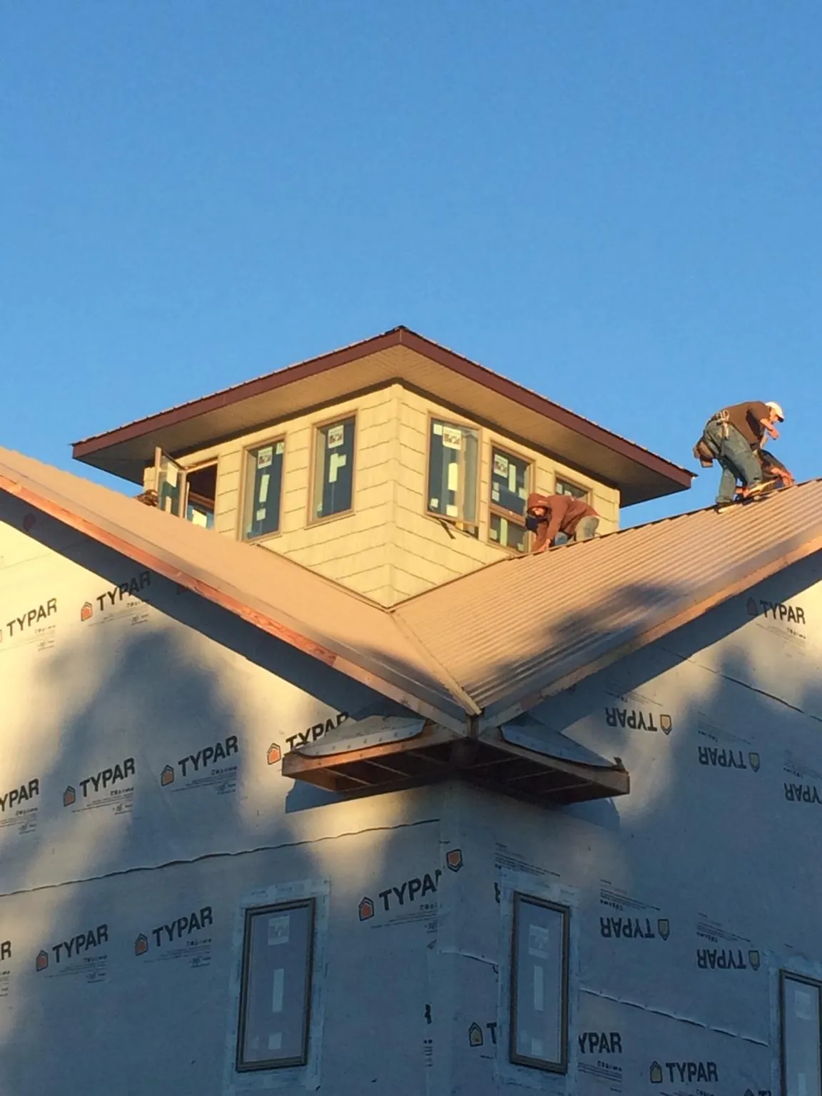 Roofers working around a rooftop cupola on a new metal roof at sunset — Roof Waterproofing in Lakemore by Roofing Brothers
